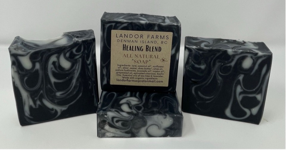 Four black Healing Blend bars with white swirls, one standing with a Landor Farms Healing Blend label