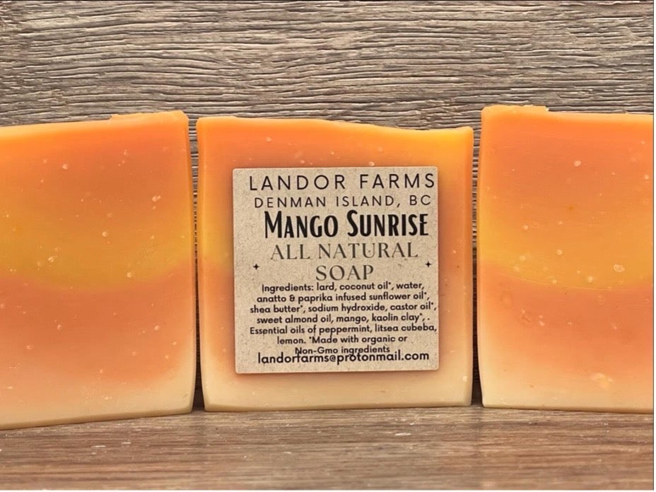 Three Mango Sunrise soap bars striped orange, yellow and cream, the middle one with a Landor Farms label, on wood