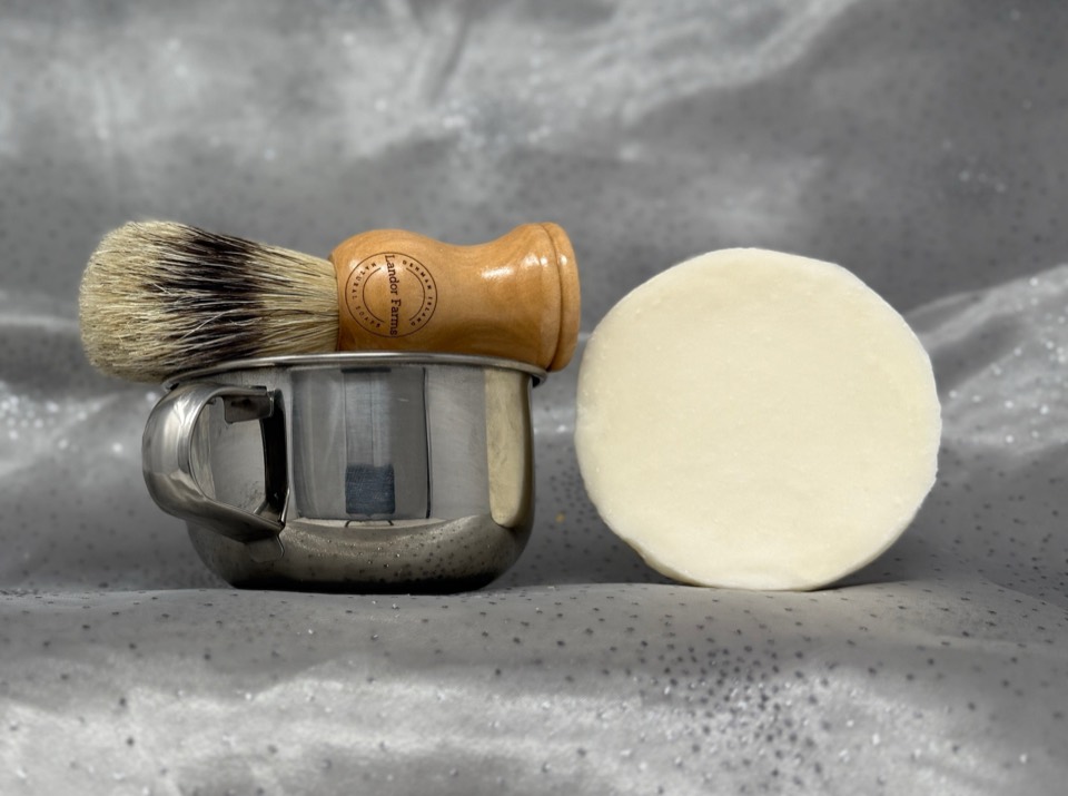 Shave Cup & Brush Set: brush stamped Landor Farms resting in a stainless-steel mug beside a round white shave bar